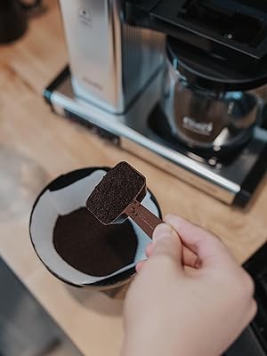 Scooping fresh coffee grounds for Technivorm Moccamaster brewing