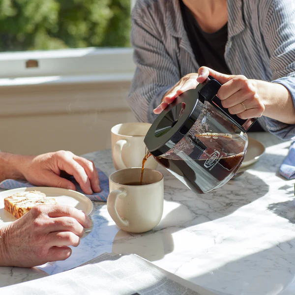 Pouring coffee from Technivorm Moccamaster into a cup at the table